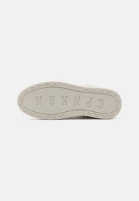 Sole of a sneaker, off-white rubber with textured grip pattern and embossed logo. Features decorative bicycle designs along the edge.