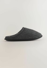 Zapatilla de lana gris con textura suave, punta redondeada y patrón a cuadros. Cuenta con una suela de goma negra para durabilidad y agarre.