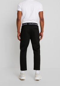 Svarta byxor med en skräddarsydd design, med en midja från Calvin Klein Jeans. Tillverkade av mjukt tyg med en slät yta och sidofickor.