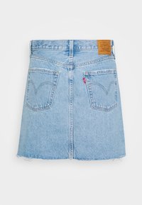 Jupe en denim bleu clair avec un ourlet brut, deux poches arrière et une étiquette de marque en cuir marron sur la taille. Coupe A-line classique.