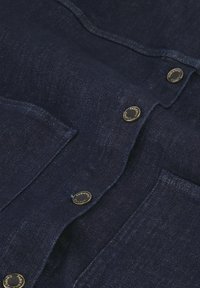 Marineblauw denim overhemd met zilverkleurige knopen, een gestructureerd oppervlak en twee borstzakken met gestikte details.
