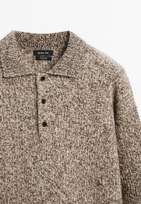 Strickpullover mit Struktur in Beige- und Brauntönen, ausgestattet mit einem Kragen, vier schwarzen Knöpfen und einem gerippten Design für zusätzliche Tiefe.
