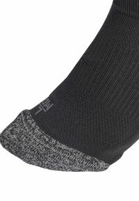 Calcetín de tobillo negro con área de punta reforzada en gris y un patrón de punto texturizado que se extiende por el pie.