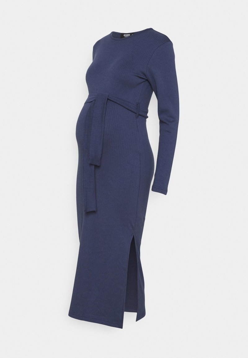 Vestido premamá azul marino con textura de canalé, de manga larga, con cinturón en la cintura y abertura lateral, presentado sobre fondo blanco.