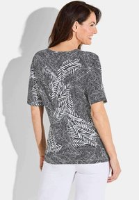 Schwarz-weißer Kurzarm-T-Shirt mit Blättermuster. Das Design hat einen runden Halsauschnitt und eine entspannte Passform.