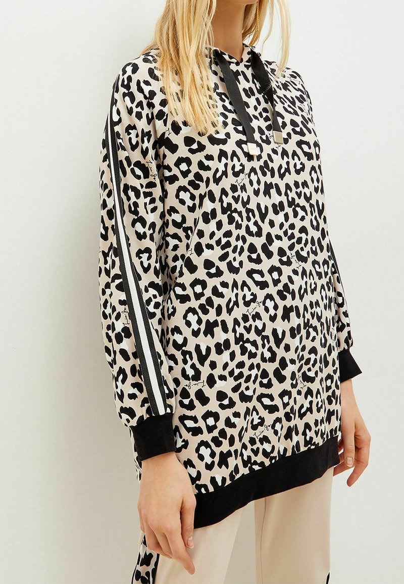 Sweat à capuche imprimé léopard en beige et noir, avec manches longues, capuche à cordon de serrage et accents noirs sur les côtés.