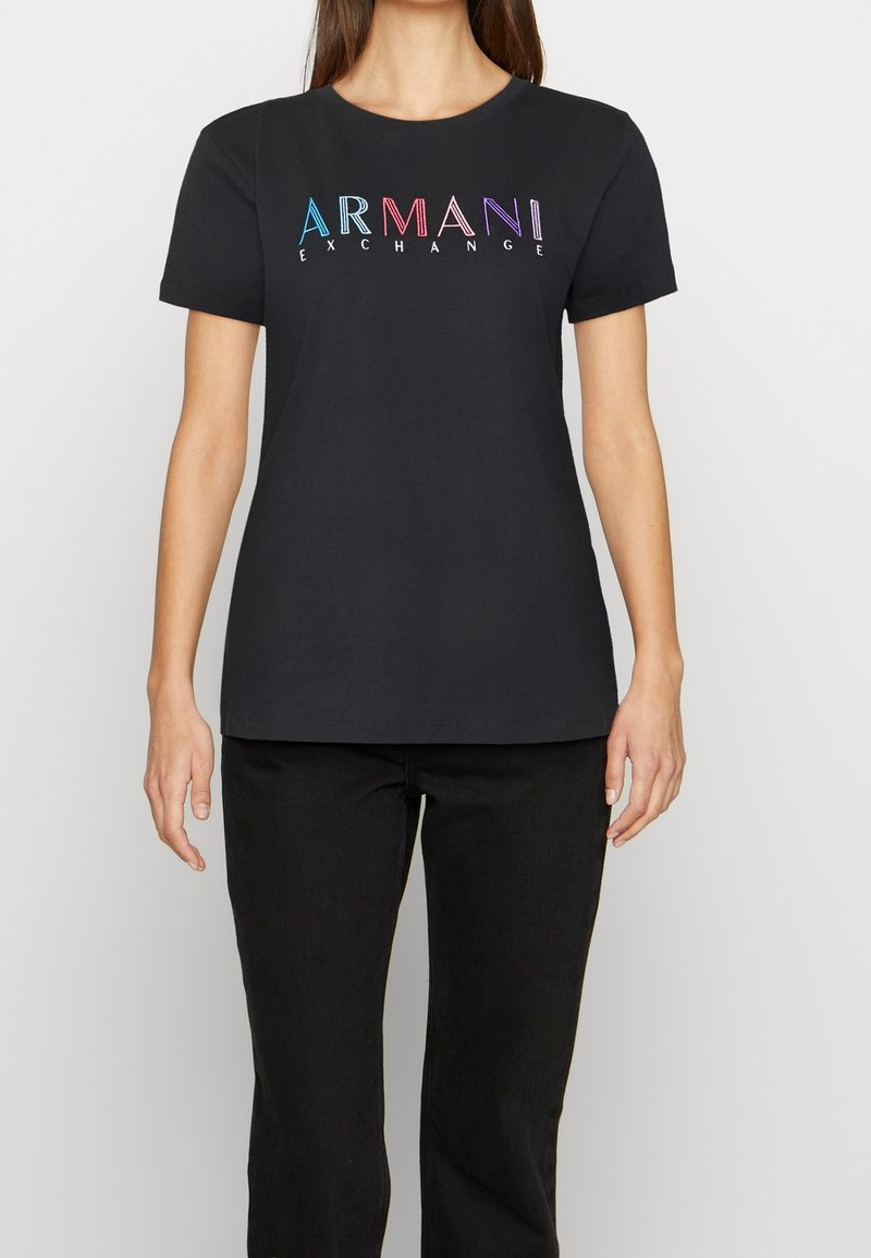 Černé bavlněné tričko s krátkými rukávy. Na hrudi se nachází vícebarevné logo "ARMANI EXCHANGE" v moderním fontu.