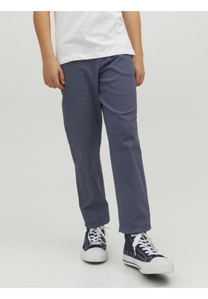 Granatowe bawełniane spodnie o luźnym kroju, prostych nogawkach i bocznych kieszeniach, zestawione z białymi i granatowymi sneakersami z białymi sznurowadłami.