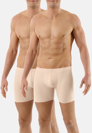 Beige Boxers aus weichem Stoff mit glatter Textur, ausgestattet mit einem mittellangen Schnitt und einem nahtlosen Bund für zusätzlichen Komfort.