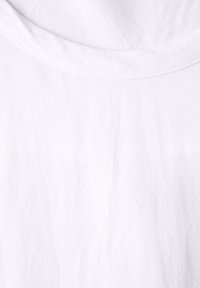 Camiseta blanca de algodón con cuello redondo, que presenta una textura suave y ligeras arrugas, sin patrones visibles ni elementos de diseño.