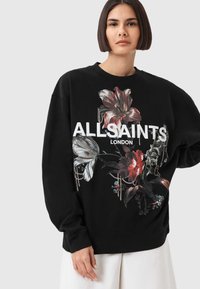 Fekete pulóver virágmintával piros és fehér színekben, rajta jól láthatóan a "ALLSAINTS LONDON" felirattal.