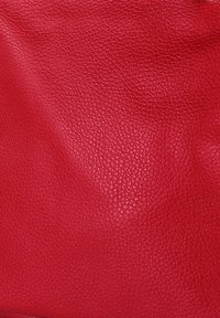 Cuir rouge texturé avec une finition en pierre, présentant une surface lisse et légèrement brillante. Idéal pour des sacs ou des accessoires.
