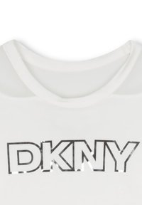 T-shirt blanc avec un col rond et des lettres "DKNY" en relief et en gras imprimées sur la poitrine.