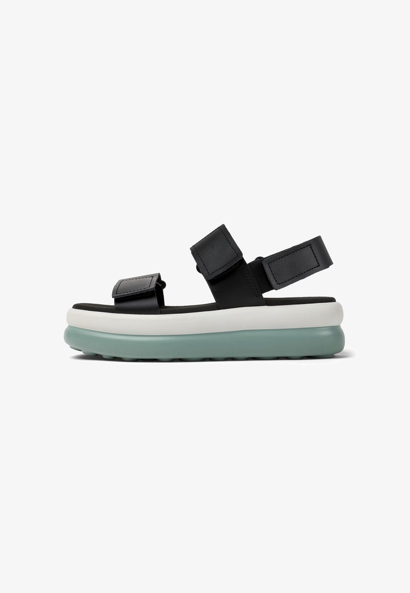 Black leather sandals with adjustable straps, a cushioned white midsole, and a light green outsole. Features a flat design and textured footbed.