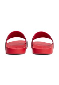 Sandales rouges avec une texture lisse, un design ouvert et sans talon. Les brides se courbent sur le pied et sont complétées par une semelle plate.