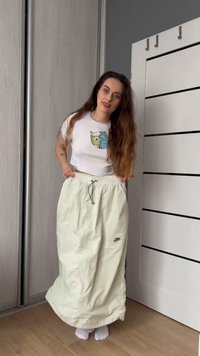 Fehér Nike sport szoknya húzózsinórral, rugalmas derékkal és oldalsó zsebekkel. Egy rövid fehér póló felett viselve, amelyen egy képregényes grafika található.