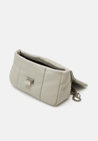 Sac à main en similicuir gris clair avec texture rembourrée, détail de fermoir métallique et bandoulière chaîne. Large ouverture pour un accès facile.