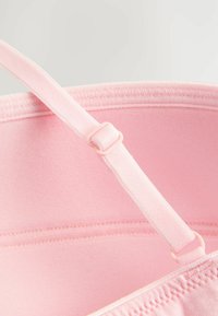 Inre av en rosa tygväska med mjuk textur, utrustad med en avtagbar rem och justerbar spänne för anpassning av längden.