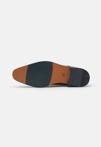 Suela de zapato de cuero marrón con una sección lisa de color tostado y goma azul texturizada, que presenta una marca de tamaño numérica (42) y un sutil patrón ondulado.