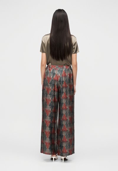 Blusa em cetim metálico cor azeitona combinada com calças largas estampadas em cinza, vermelho e preto, com cós elástico.