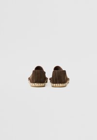 Brune semskede slip-on sko med et vevet jute trim. Rundt bakdesign, glatt tekstur og minimalistisk stil. Egner seg for uformell bruk.