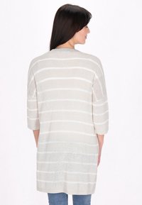 Cardigan lungo beige chiaro con strisce orizzontali bianche, maniche 3/4, texture a maglia e una vestibilità rilassata, che termina appena sopra i fianchi.