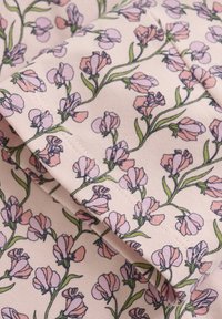 Blommönstrad tyg med små rosa och lila blommor på en ljusrosa bakgrund, med gröna stjälkar och blad, och synlig sömnad.