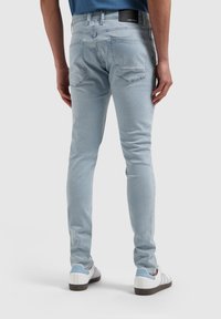 Lichtblauwe denim met een slim fit, vijf-pocket design en subtiele textuur. De achterkant heeft twee zakken en een leren label met merknaam op de taille.