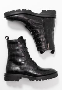 Botas de tobillo de cuero negro con textura de cocodrilo, cordones en la parte delantera, cremallera lateral y suelas resistentes con surcos prominentes.