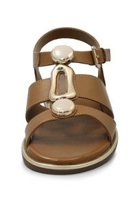 Sandal in pelle marrone con tre cinghie, dettagli dorati e due embellishments rotondi. Cinturino regolabile alla caviglia e suola piatta.