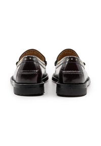 Mocassini in pelle bordeaux con finitura lucida, dotati di borchie in tonalità oro lungo la cucitura, suole in gomma nera piatta e punta arrotondata.