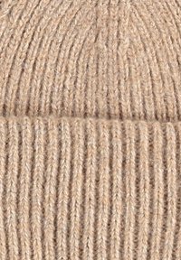 Knit beanie in beige wool, featuring a ribbed texture and a turned-up cuff at the bottom, providing warmth and a snug fit.