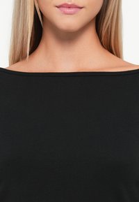 Crna bluzica bez naramenica s glatkom teksturom i širokim izrezom, koja ima prilagođen kroj i minimalne šavne detalje.