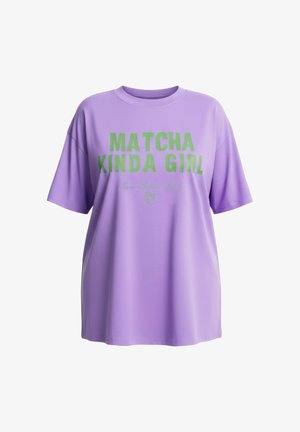 Levandulové oversize tričko se zeleným nápisem „MATCHA KINDA GIRL“ a menším kurzívním textem dole s malou ikonou nápoje matcha.