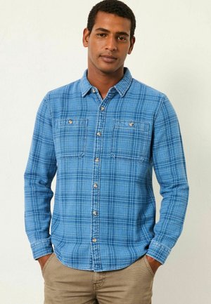 Blau kariertes Hemd mit Button-Down-Kragen, zwei Brusttaschen und Holzknöpfen. Lange Ärmel mit tailliertem Schnitt.