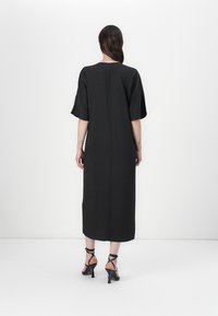 Black, ankle-length dress with short, wide sleeves and a straight silhouette. Smooth fabric texture and a center back seam detail.