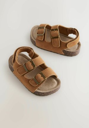 Bruine suède sandalen met twee verstelbare bandjes en messing gespen, voorzien van een gevoerde binnenzool en een textuurrijke, lichte zool.