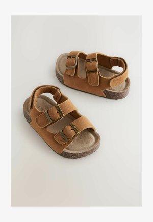 Sandali in pelle scamosciata marrone con due cinturini regolabili e fibbie in ottone, dotati di una soletta imbottita e una suola leggera e strutturata.