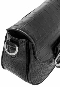 Czarna torebka skórzana o wzorze krokodyla z klapą, srebrnymi akcentami i zorganizowanym kształtem. Widoczne detale tekstury.