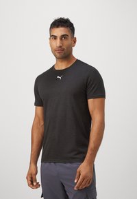 Zwarte t-shirt met korte mouwen gemaakt van lichtgewicht stof. Het heeft een ronde halslijn en een klein wit Puma-logo op de borst.