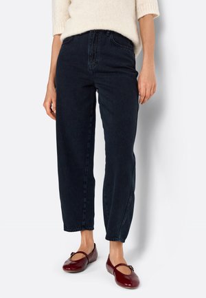 Jean en denim bleu foncé avec une taille haute, une coupe décontractée et des jambes droites, associés à des ballerines bordeaux avec un détail décoratif.
