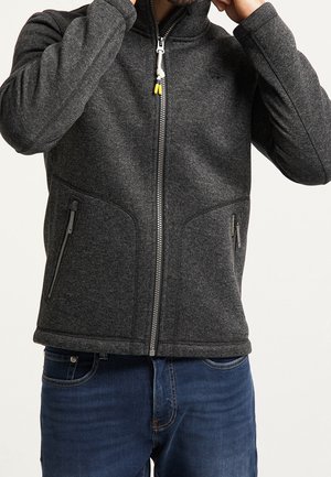 Gray zip-up jacket made of textured fabric, featuring two side pockets and a high collar. Includes yellow and white pull cord detail.