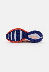 Suola di una scarpa da corsa con battistrada blu e arancione, strisce di presa bianche e un piccolo logo Nike visibile su uno sfondo bianco.