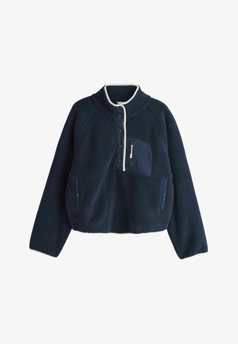 Pull polaire bleu marine avec bordure blanche, boutons-pression sur le devant, poche poitrine zippée et deux poches latérales à boutons-pression.