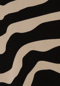 Tessuto nero e beige con strisce astratte ondulate. Il materiale appare morbido con una texture opaca.