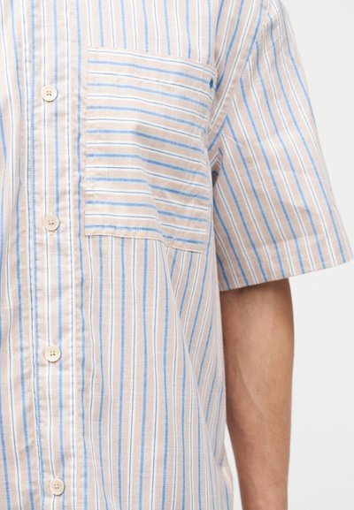 Ανοιχτό μπεζ πουκάμισο κοντών μανικιών με κάθετες μπλε και λευκές ρίγες, κουμπιά μπροστά και τσέπη στο στήθος σε σώμα ανθρώπου.