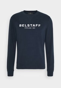 Mörkblå sweatshirt i bomull med ribbad mudd och nederkant. Har stora vita bokstäver med texten "BELSTAFF ENGLAND 1924" över framsidan.