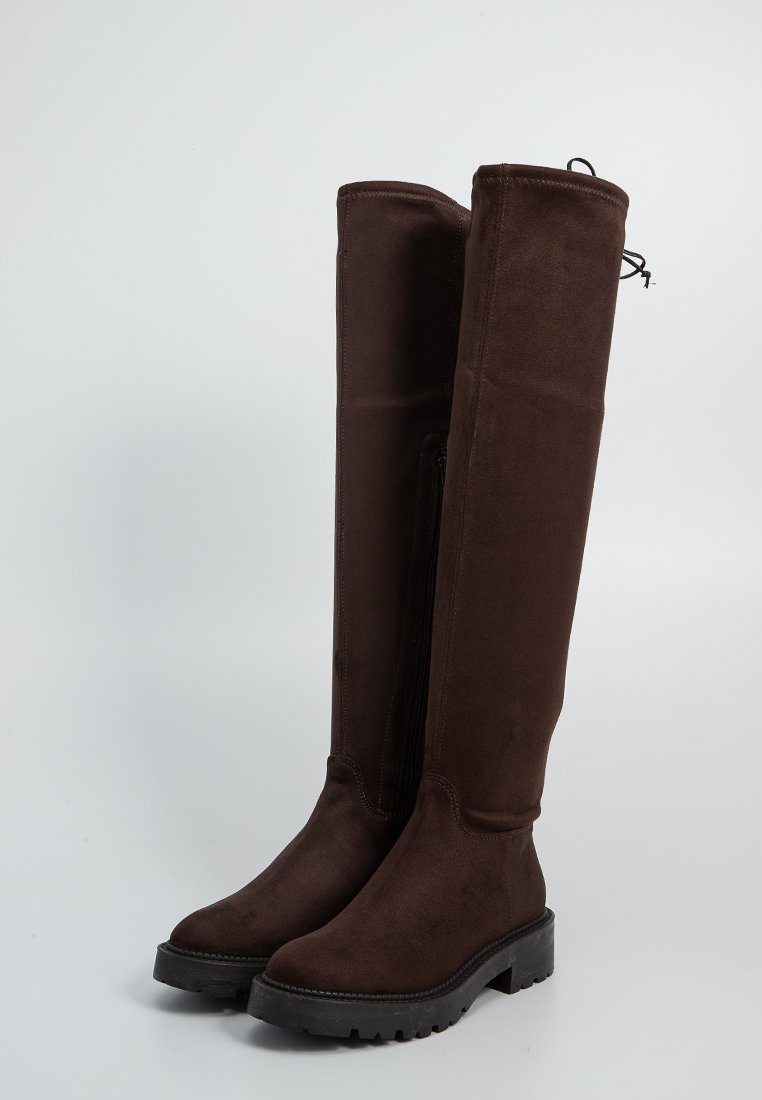 Stivali al ginocchio in suede marrone con una finitura texture, suola in gomma piatta e zip laterale per una facile calzata. Stringa regolabile nella parte superiore.