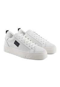 Hvite sneakers med strukturert krokodille-embossed materiale, flate lisser, polstret krage og en kontrasterende svart løkke på hælen. Tyk gummi såle.