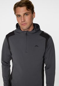 Grå zip-up hoodie med svarta accenter och logotyp. Tillverkad av mjukt tyg, har en huva och långa ärmar med en figurnära design.